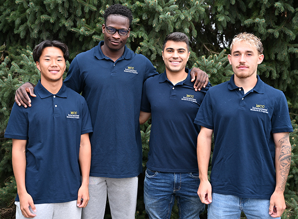 the four international ambassadors standing together with a pine tree background