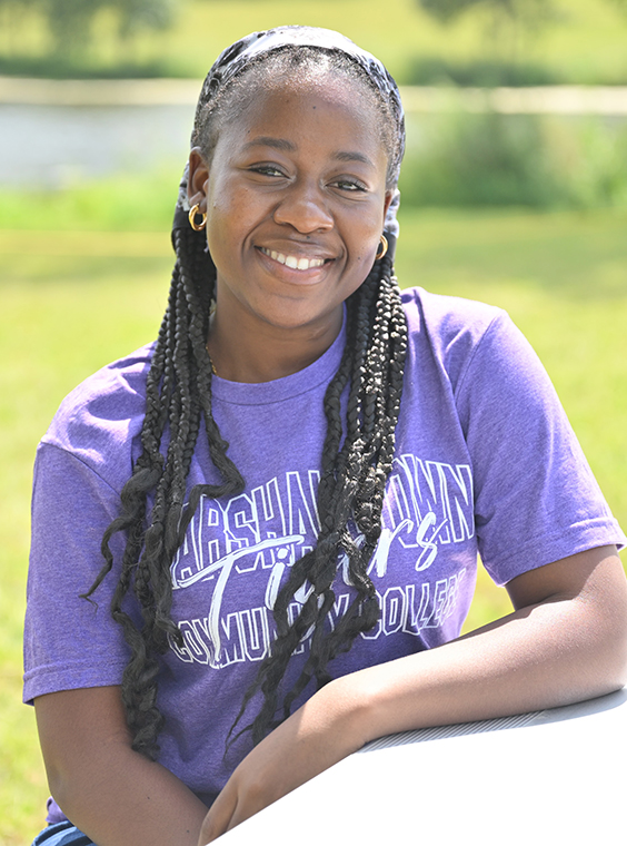 Ketsia Mulunda sitting outdoors at the MCC campus smiling for the camera