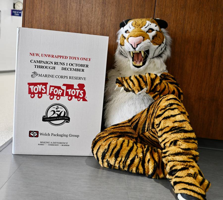 The MCC Tiger posing text to a Toys for Tots collection box