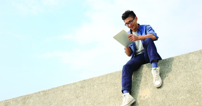 a-stock-photo-of-a-man-sitting-on-a-ledge-with-a-tablet