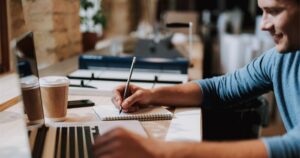 a-stock-photo-of-a-man-in-a-coffeehouse-with-his-laptop-and-notepad