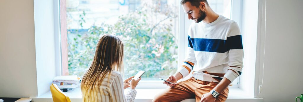 a-header-image-used-for-a-blog-post-which-features-a-man-and-woman-sitting-together-on-their-phones