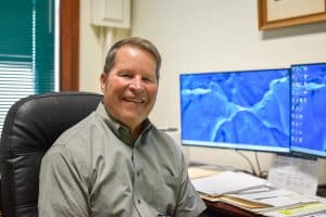 Roger Nissly sits at his desk in front of his computer.